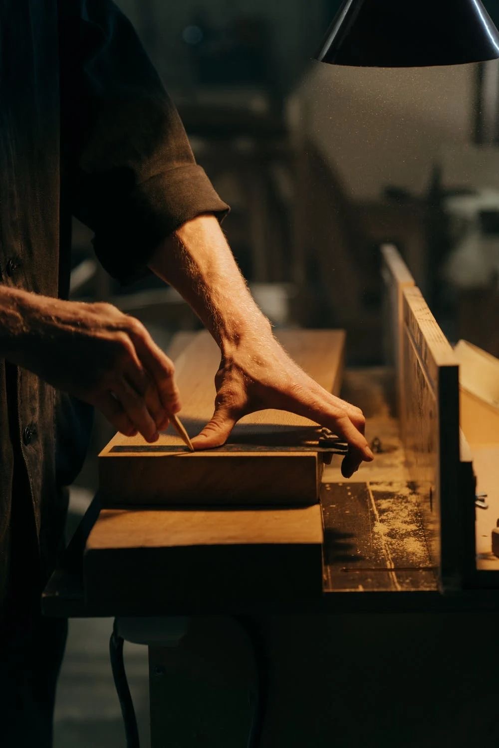 Hands marking a line on a timber beam in a workshop